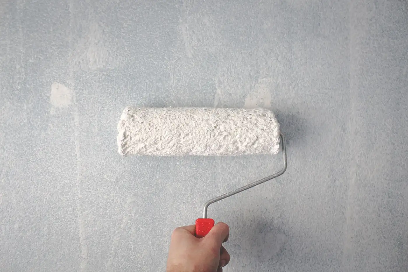 Illustrative photo of a hand rolling white paint onto a wall. Not ATR Decorators staff or a job of theirs.